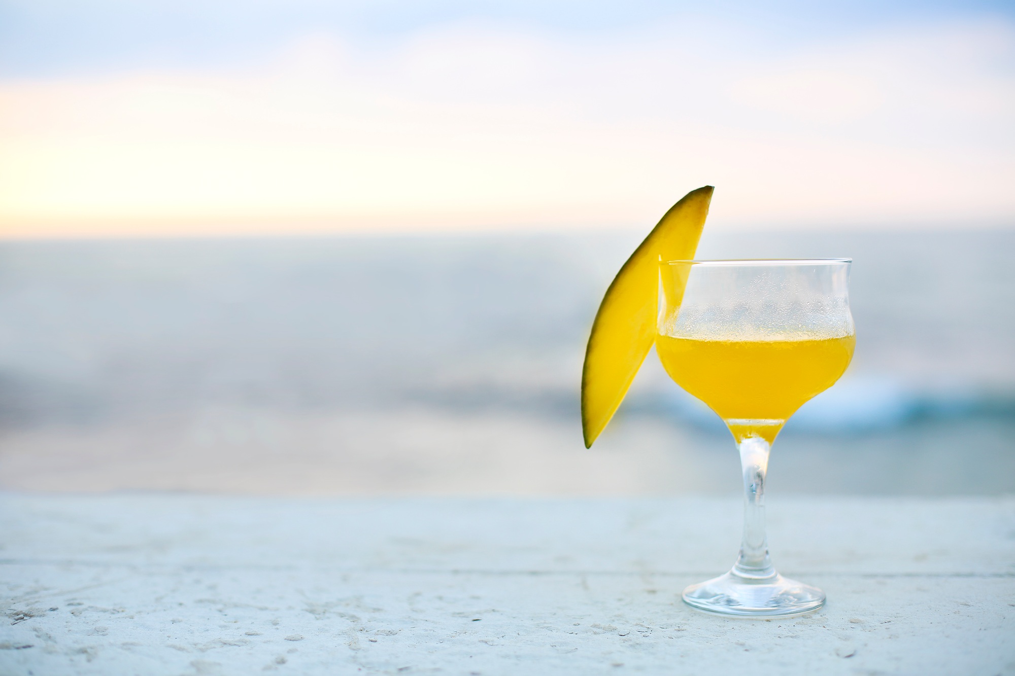 Glass of mango cocktail on bar counter